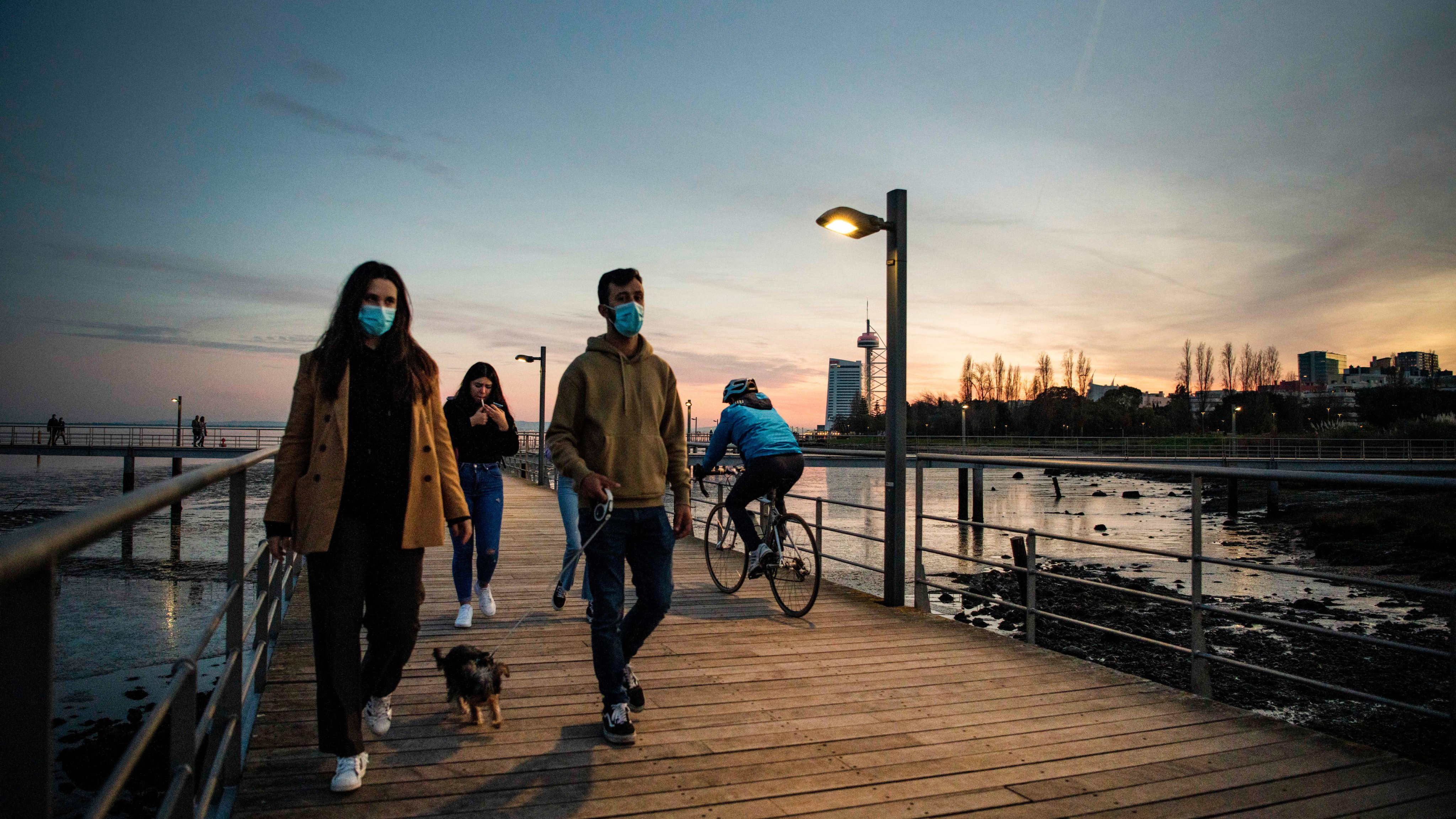 People wearing face masks are seen walking along the Tagus