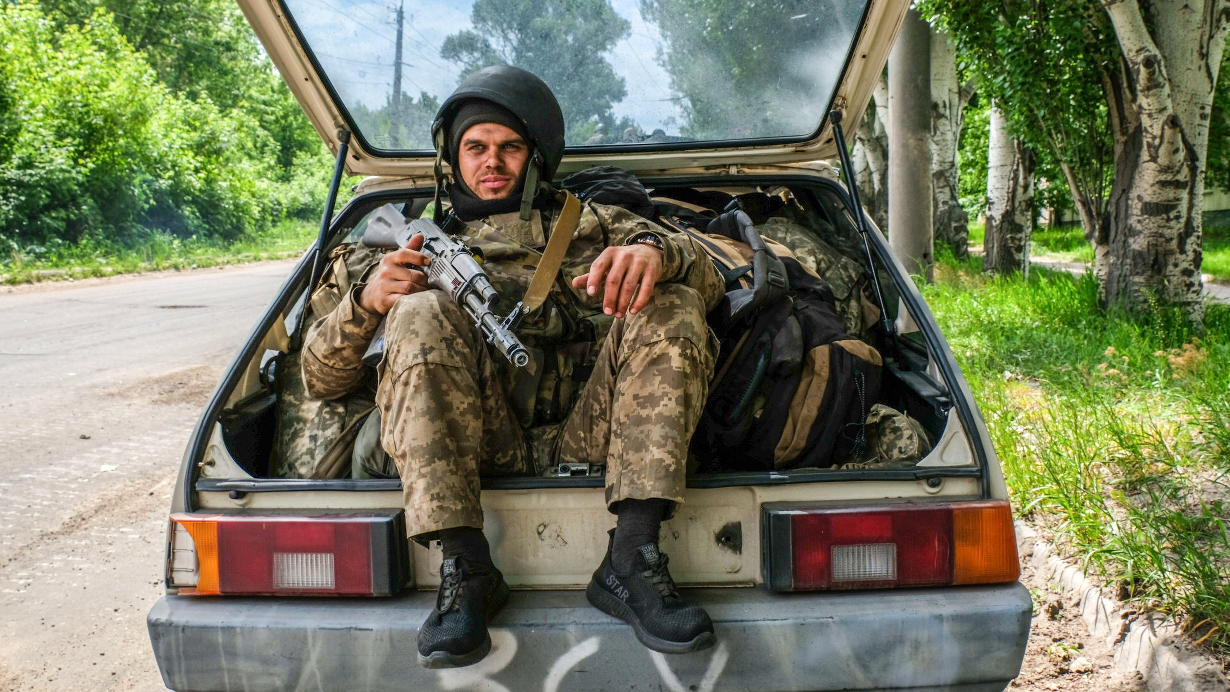 A soldier seen sitting in a car trunk full of backpacks