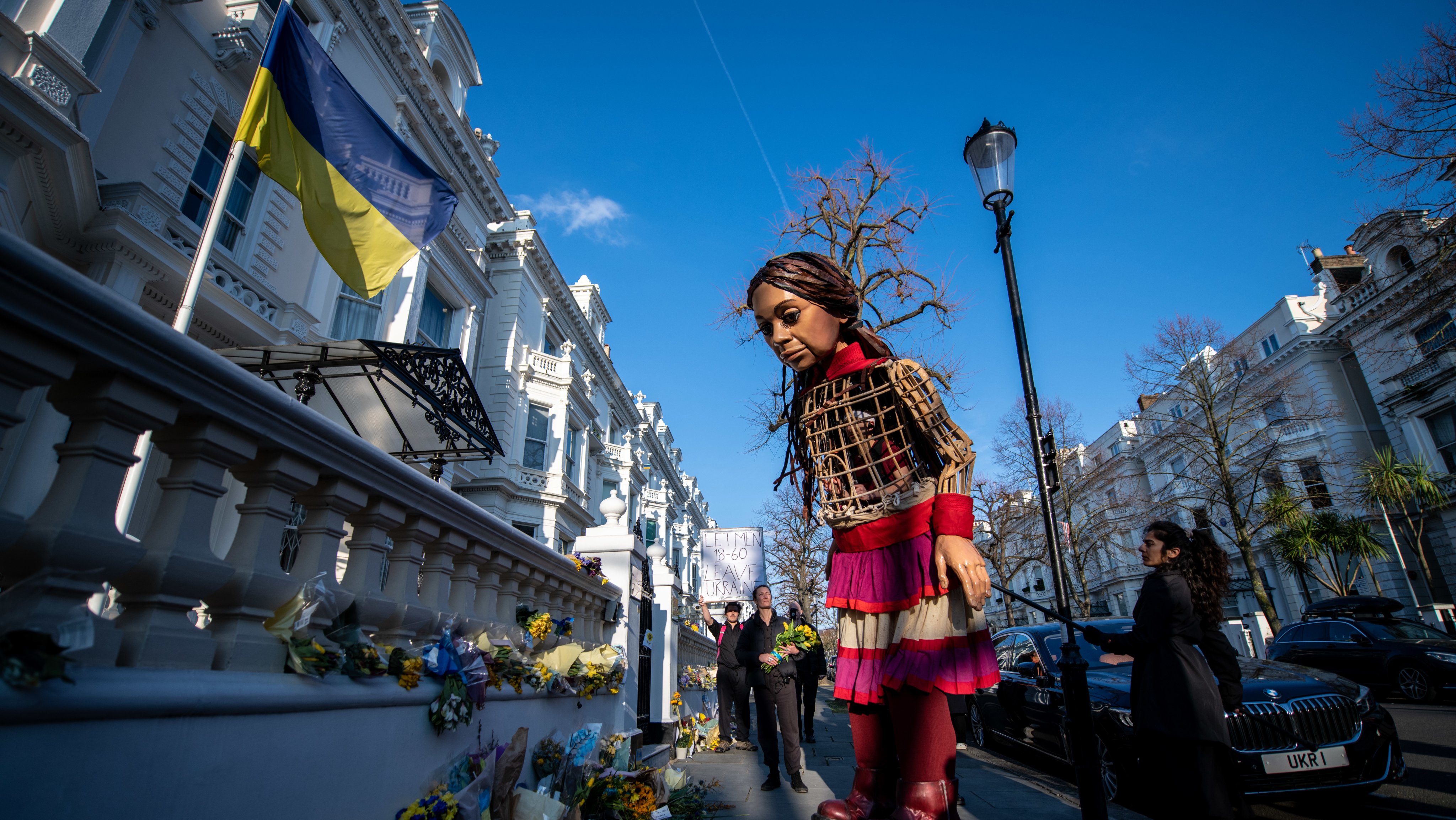 A &quot;Pequena Amal&quot;, fantoche que representa uma criança síria refugiada, coloca flores na embaixada da Ucrânia em Londres
