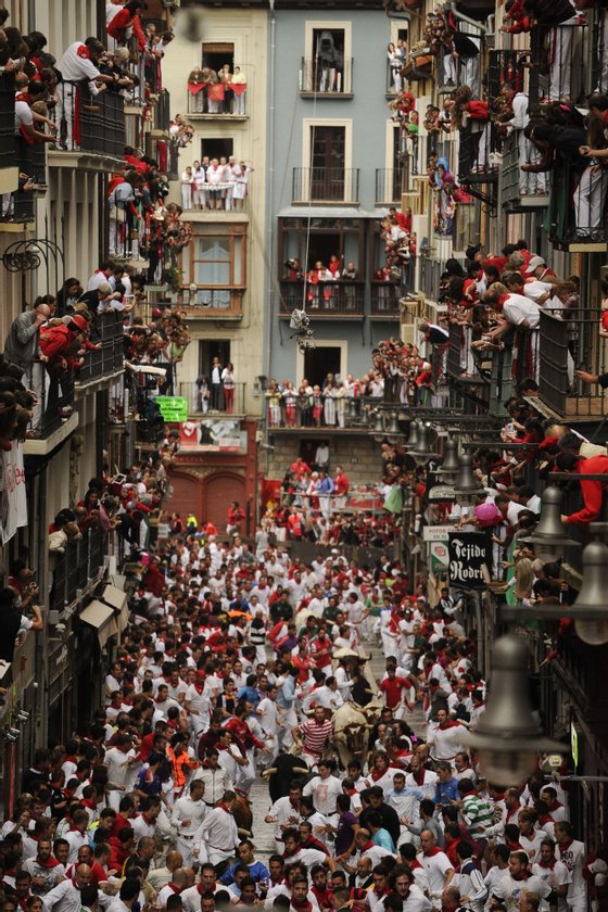 People standing on balconies look at participants as they run in front of Victoriano del Rio Cortes' bulls during the third bull-run of the San Fermin Festival in Pamplona, northern Spain, on July 9, 2014. The festival is a symbol of Spanish culture that attracts thousands of tourists to watch the bull runs despite heavy condemnation from animal rights groups.  AFP PHOTO / PEDRO ARMESTRE        (Photo credit should read PEDRO ARMESTRE/AFP/Getty Images)