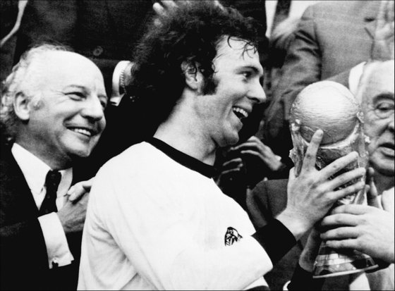 MUNICH, GERMANY - JULY 7:  Germany's soccer star and team captain Franz Beckenbauer receives the World Soccer Cup won by his team after a 2-1 victory over Holland 07 July 1974 at Munich's Olympic stadium, as West Germany president Walter Scheel (L) applauds.   Franz Beckenbauer, le capitaine de l'Tquipe d'Allemagne, retoit la Coupe du Monde de Football 1974, a Munich le 07 juillet 1974.  (Photo credit should read STF/AFP/Getty Images)