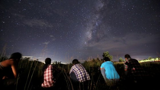 This long-exposure photograph taken on August 12, 2013 shows people watching for the Perseid meteor shower in the night sky near Yangon. The meteor shower occurs every year in August when the Earth passes through the debris and dust of the Swift-Tuttle comet.   AFP PHOTO / Ye Aung Thu        (Photo credit should read Ye Aung Thu/AFP/Getty Images)