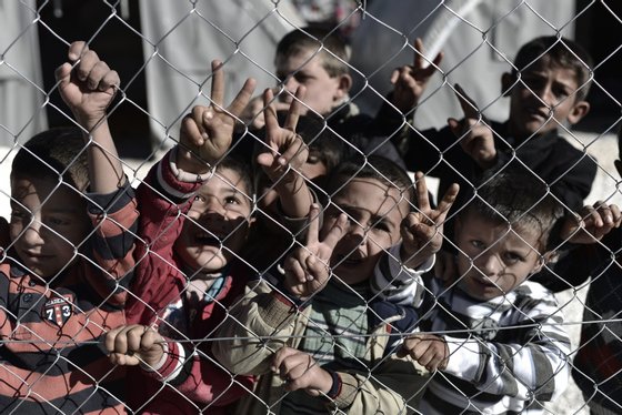 Young Syrian Kurdish boys make the "V for victory" sign behind a fence at a refugee camp in the town of Suruc, Sanliurfa province, on November 5, 2014. Iraqi Kurdish peshmerga fighters who joined the battle for the Syrian border town of Kobane have been heavily shelling Islamic State group jihadists, a commander told AFP. AFP PHOTO / ARIS MESSINIS (Photo credit should read ARIS MESSINIS/AFP/Getty Images)