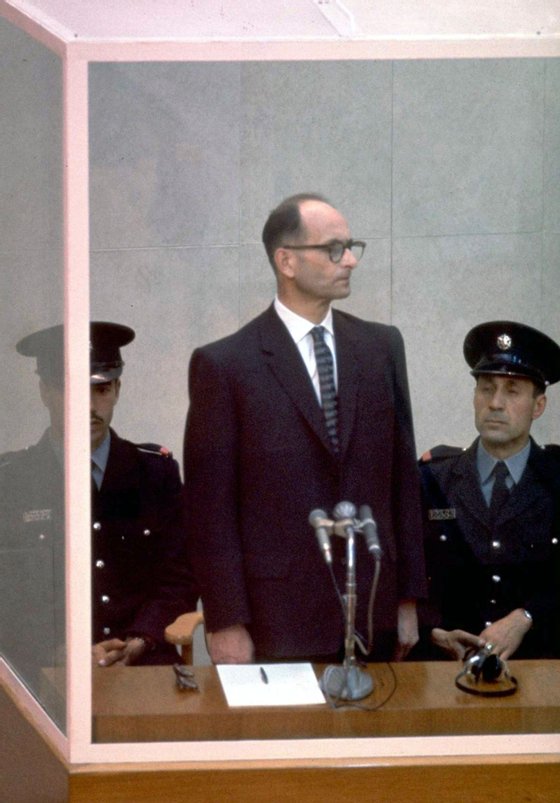JERUSALEM, ISRAEL: (FILE PHOTO) Nazi war criminal Adolph Eichmann stands in a protective glass booth flanked by Israeli police during his trial April 21, 1961 in Jerusalem. The Israeli police donated Eichmann's original handprints, fingerprints and mugshot to Jerusalem's Yad Vashem Holocaust memorial ahead of Israel's annual Holocaust remembrance day May 4, 2005 which this year also marks the 60th anniversary of the Nazi's World War II defeat in 1945. (Photo by John Milli/GPO via Getty Images)