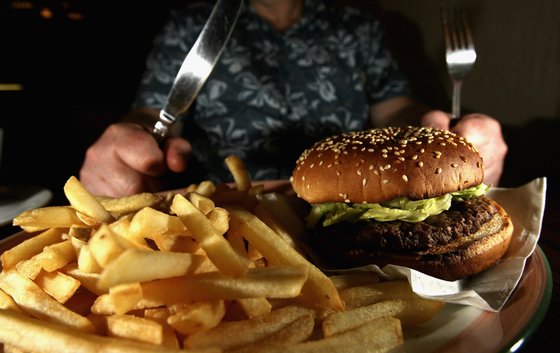 GLASGOW, UNITED KINGDOM - JUNE 07:  In this photo illustration a man eats a hamburger ind chips in a cafe on June 7,2006 in Glasgow, Scotland. New figures are suggesting that a large proportion of the population is clinically obese.  (Photo Illustration by Jeff J Mitchell/Getty Images)