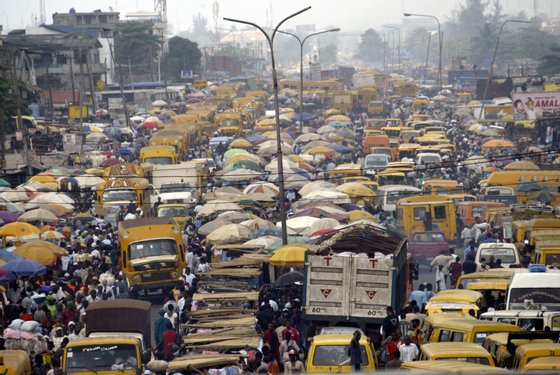 People walk struggling for space between public transport buses and trucks at the burstling Oshodi bus stop in Lagos 06 February 2006. Lagos is reputed as one of the mostly densely populated city in the world with population more than 14 million. AFP PHOTO/PIUS UTOMI EKPEI (Photo credit should read PIUS UTOMI EKPEI/AFP/Getty Images)