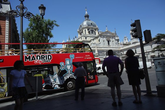 MADRID, SPAIN - JULY 07: Tourists ride a sightseeing bus past the Catedral de la Almudena on July 7, 2012 in Madrid, Spain. Despite having the fourth largest economy in the Eurozone, the economic situation in Spain remains troubled with their unemployment rate the highest of any Eurozone country. Spain is currently administering billions of euros of spending cuts and tax increases in a bid to manage its national debt. Spain also has access to loans of up to 100 billion euros from the European Financial Stability Facility which will be used to rescue the country's banks that have been badly affected by a crash in property prices. (Photo by Oli Scarff/Getty Images)