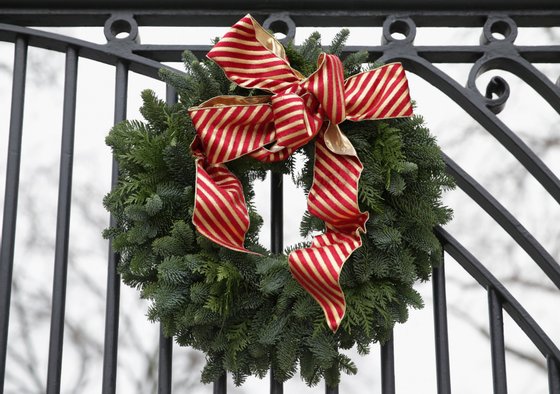 WASHINGTON, DC - DECEMBER 04: A Christmas wreath is hung on a gate of the White House December 4, 2013 in Washington, DC. U.S. first lady Michelle Obama will host today military families for the first viewing of the 2013 holiday decorations and demonstrating holiday crafts and treats to military children. (Photo by Alex Wong/Getty Images)