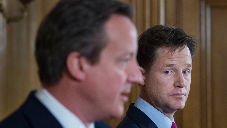 Clegg olha de lado para Cameron numa conferência de imprensa