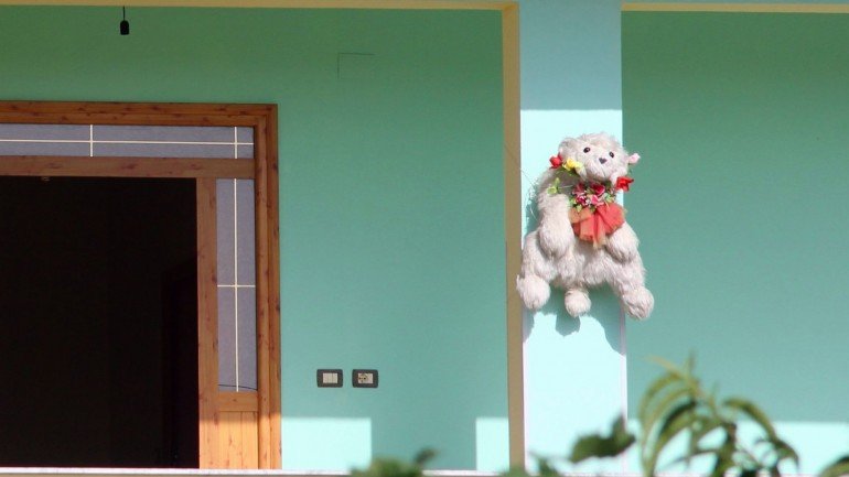 Há peluches, coelhos e bonecas pendurados em algumas portas da Albânia