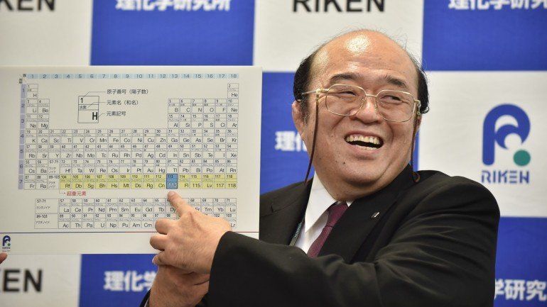 Um dos cientistas japonês aponta para o elemento 113 no anúncio das descobertas