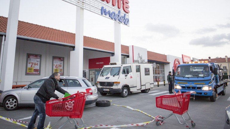Na fotografia vê-se o carro onde os assaltantes chegaram à porta do supermercado em Lourel e a carrinha de valores que acabou por não ser assaltada