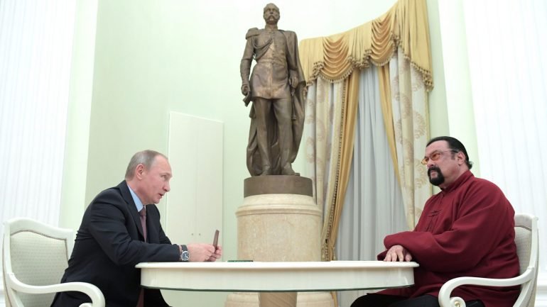 O Presidente russo, Vladimir Putin, a assinar o passaporte russo de Steven Seagal (à direita)