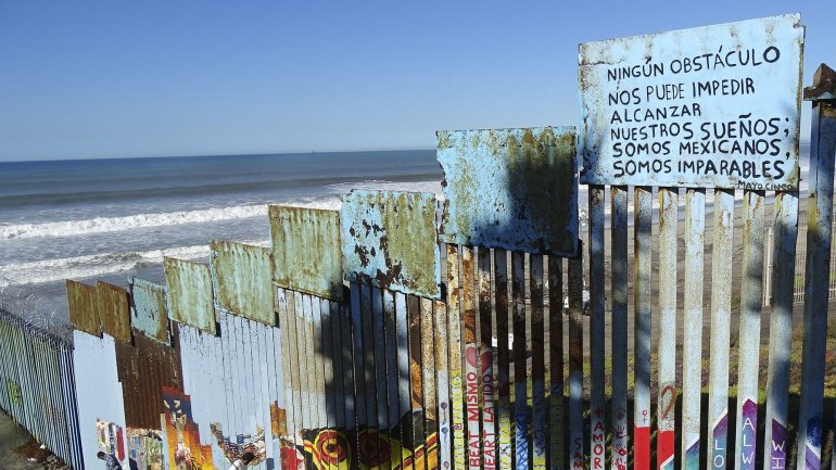 Um cartaz onde se lê em português &quot;Nenhum Obstáculo nos Pode Impedir Alcançar os Nossos Sonhos; Somos Mexicanos, Somos Imparáveis.&quot; preso ao muro que divide a fronteira entre o México e os Estados Unidos, em Tijuana, México, 7 de dezembro de 2018