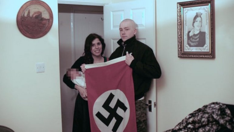 Cláudia Patatas e o companheiro, Adam Thomas, com o bebé coberto pela bandeira nazi -- Fotografia: Departamento da Polícia de West Midlands