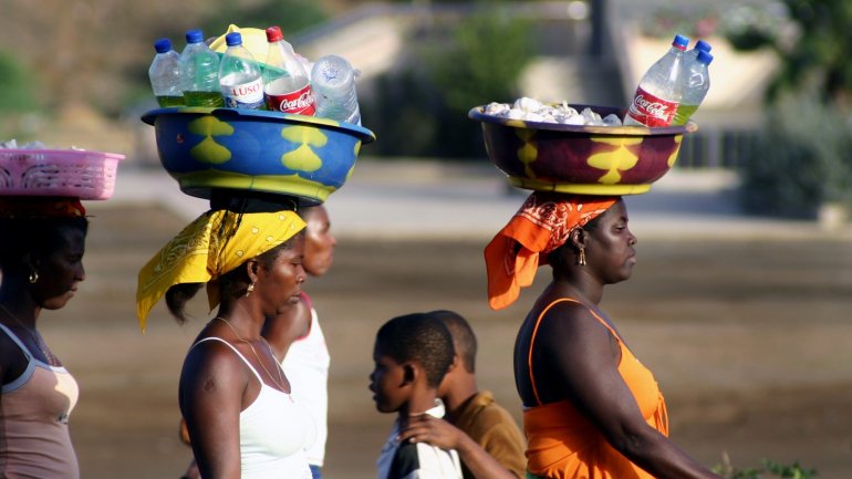 Mulheres cabo-verdianas transportam mercadorias à cabeça, a caminho do mercado na Cidade da Praia