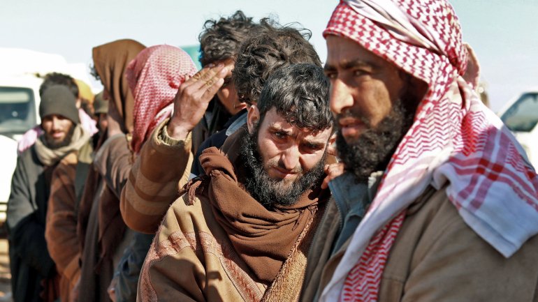 Um grupo de homens, suspeitos de terem combatido pelo Estado Islâmico, aguarda a sua vez de serem vendados após serem detidos pelas SDF