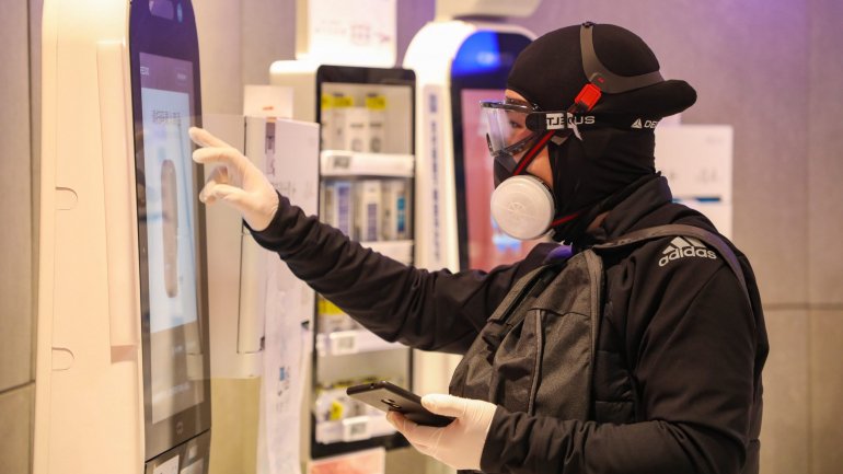 Um homem completamente protegido contra o vírus faz compras num supermercado em Wuhan