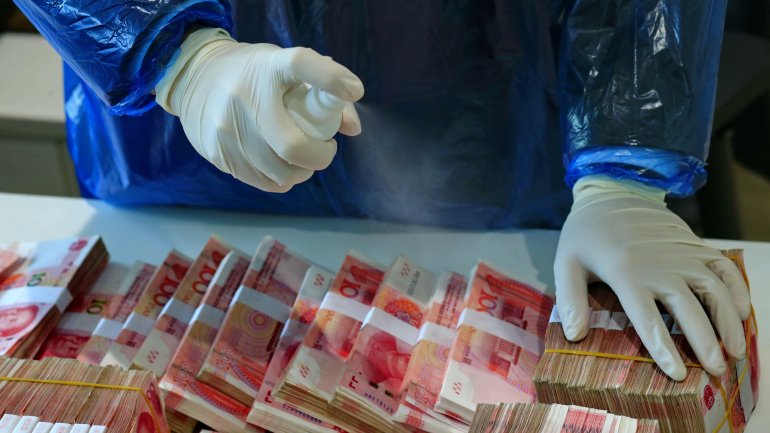 Funcionário de um banco desinfeta notas em Sinchuin, na China