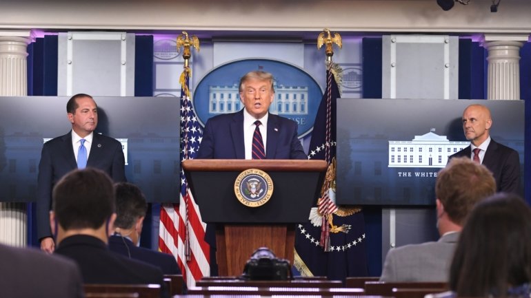 O Presidente dos Estados Unidos, Donald Trump, acompanhado de Alex Azar (à esquerda), secretário da Saúde e Serviços Humanos, e o comissário da FDA Stephen Hahn (à direita)